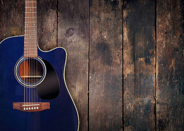 Guitar and wood background A blue acoustic guitar resting against a rustic wooden background with moody lighting. All branding/labels removed to avoid copyright issues. musical instrument bridge stock pictures, royalty-free photos & images
