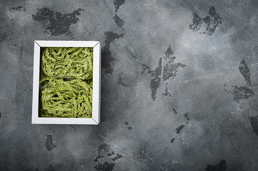 Raw green pasta pack set, on gray stone table background, top view flat lay, with copy space for text