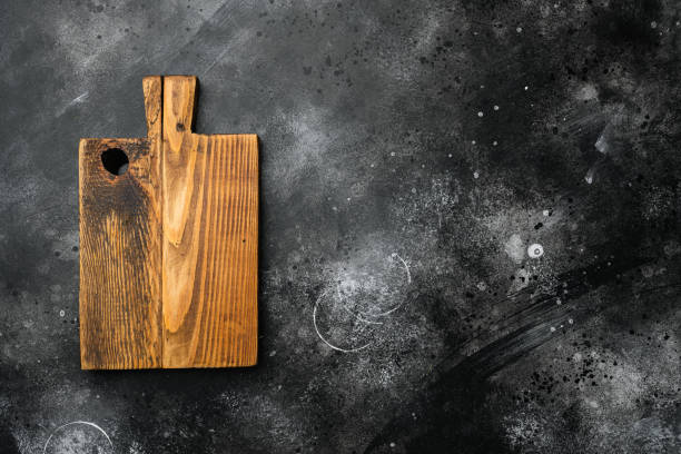 istock Aged wood cutting board, top view flat lay , with copy space for text or food, on black dark stone table background 1349316420