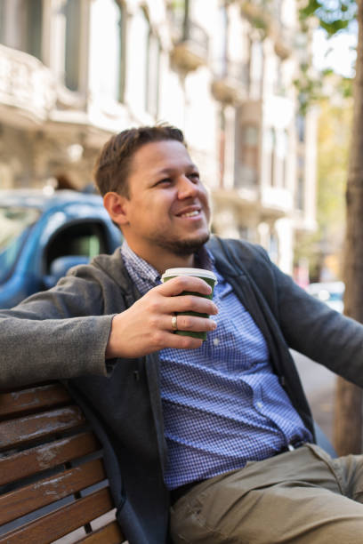 istock Smiling man drinking coffee sitting in the bench 1349317842