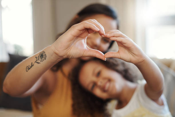 Shot of an unrecognizable woman bonding with her daughter at home and making a heart-shaped gesture We've got lots of love to share heart hands multicultural women stock pictures, royalty-free photos & images