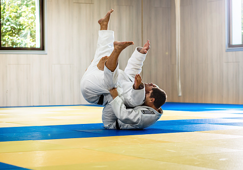 Two adult man practicing judo in the sports hall.
