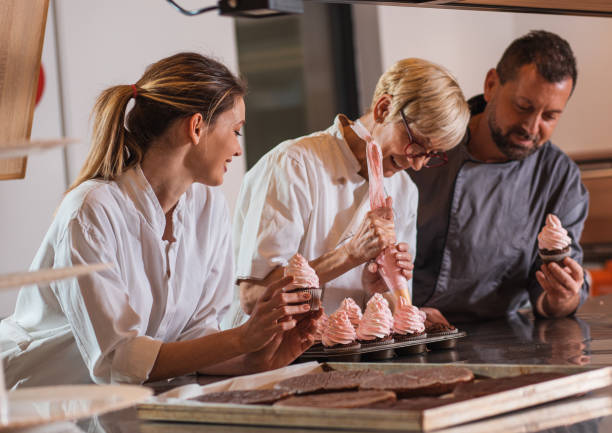 istock Group of bakers in uniform decorating desserts in modern manufacturing. 1349323783