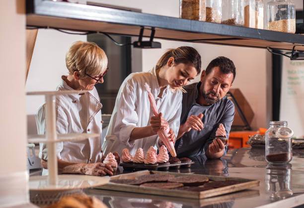 istock Group of bakers in uniform decorating desserts in modern manufacturing. 1349323785