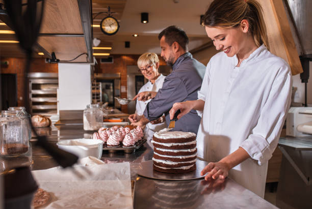 istock Group of bakers in uniform decorating desserts in modern manufacturing. 1349323834
