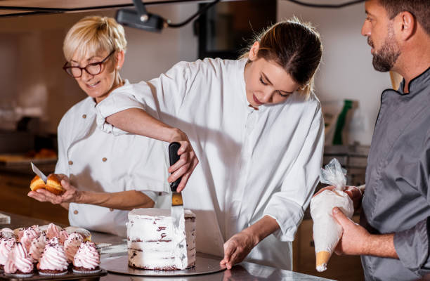 istock Group of bakers in uniform decorating desserts in modern manufacturing. 1349323903