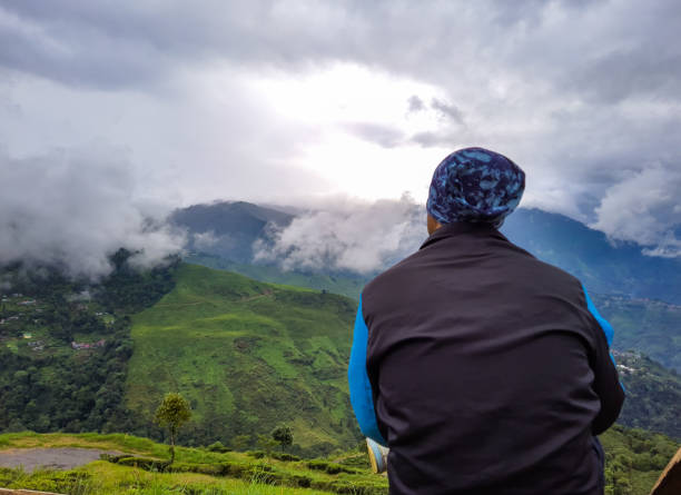 man sitting at mountain top with dramatic sky at morning