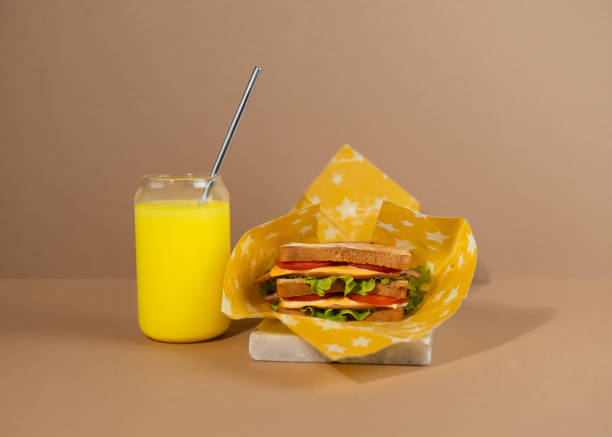 A traditional sandwich made from toasted bread slices, cheese, ham, fresh salad wrapped in organic beeswax paper. A traditional sandwich made from toasted bread slices, cheese, ham, fresh salad wrapped in organic reusable beeswax paper. Celebrating National Sandwich Day. beeswax wrap stock pictures, royalty-free photos & images