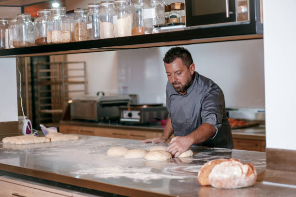 istock Male baker preparing dough for bread in modern manufacturing. 1349324975