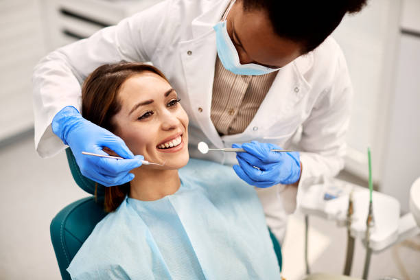 junge glückliche frau während des zahnärztlichen eingriffs in der zahnarztpraxis. - zahnarztpraxis stock-fotos und bilder