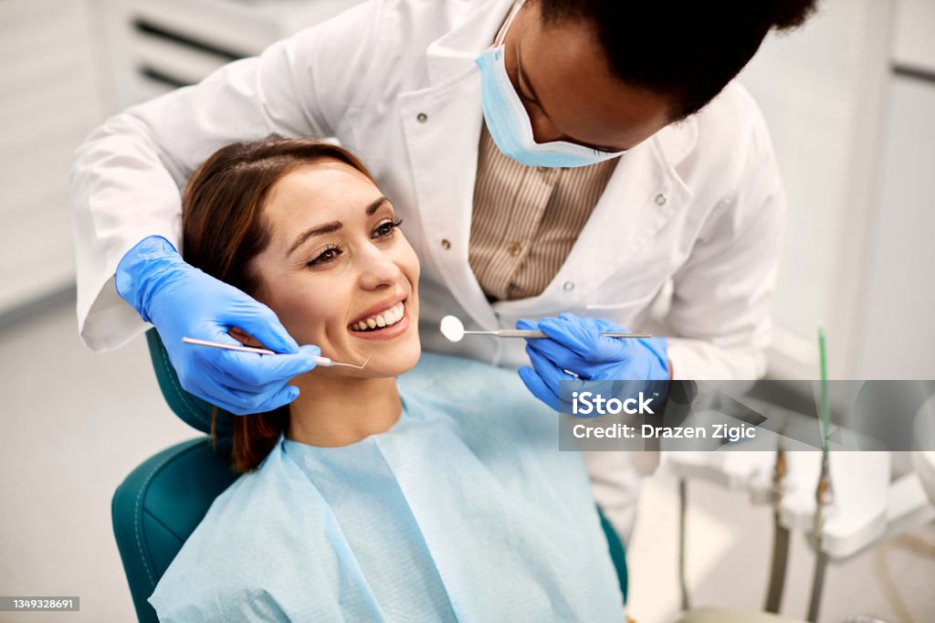 Young happy woman during dental procedure at dentist's office. Happy woman having her teeth checked during appointment at dental clinic. Dentist Stock Photo