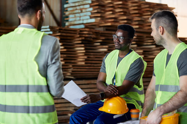 istock Happy black worker and his colleague having a meeting with their manager while working at wood warehouse. 1349328724