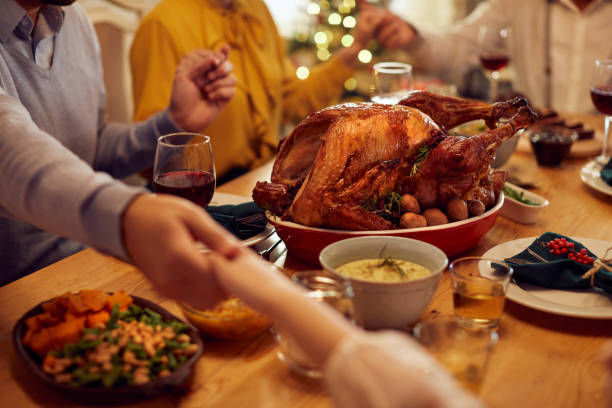 primer plano de la familia diciendo gracia durante la comida de acción de gracias en la mesa del comedor. - family thanksgiving dinner praying fotografías e imágenes de stock