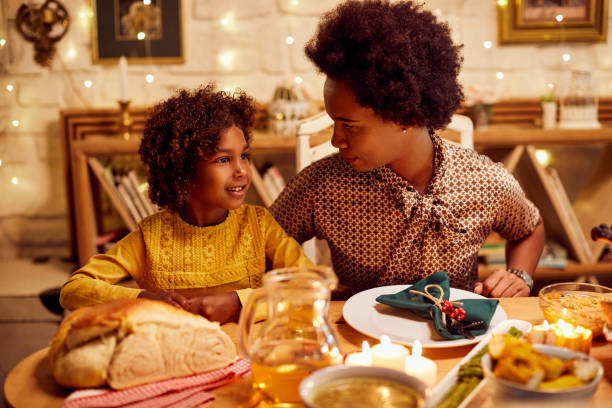 istock Smiling black girl and her mother talking while having Thanksgiving lunch at dining table. 1349328736