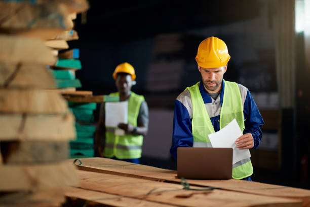 istock Warehouse foreman working on laptop at wood distribution compartment. 1349328743
