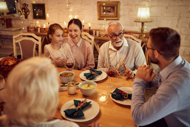 istock Happy extended family talking while gathering at dining table for Thanksgiving lunch. 1349328899