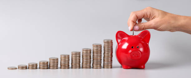 Woman tosses coin into piggy bank closeup stock photo