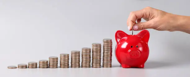 Woman tosses coin into piggy bank. Smart storage of savings concept