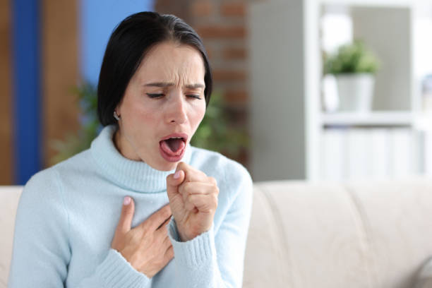 istock Woman with coughing fits sits on couch closeup 1349329673