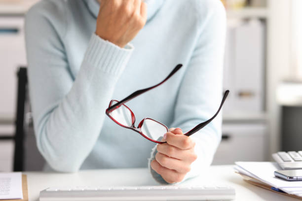 istock Woman holding glasses in hands while sitting at workplace 1349329688