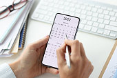 Smartphone on screen with calendar for 2022 pen in female hands