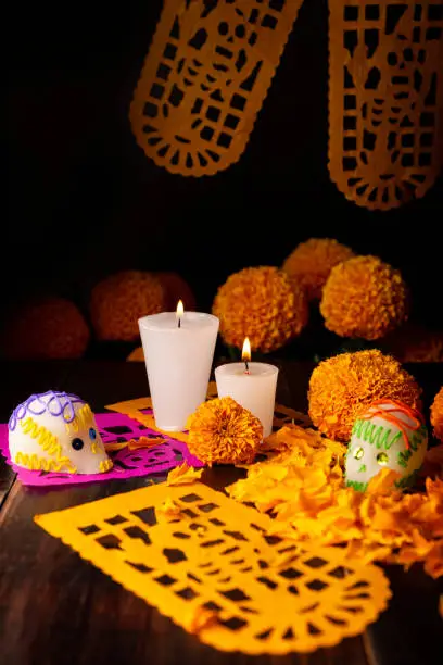 Sugar skulls with Candles, Cempasuchil flowers or Marigold and Papel Picado. Decoration traditionally used in altars for the celebration of the day of the dead in Mexico