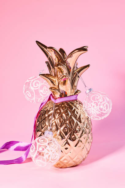 istock Artificial gold colored pineapple decorated with transparent Christmas balls on pink background. Alternative Christmas tree 1349337202