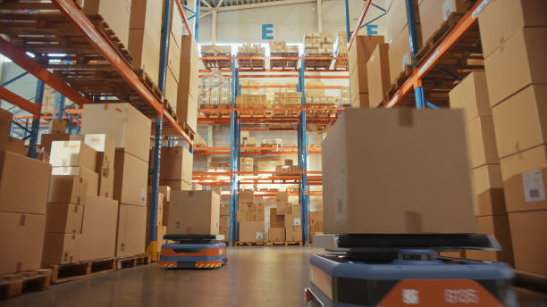istock Future Technology 3D Concept: Automated Modern Retail Warehouse AGV Robots Transporting Cardboard Boxes in Distribution Logistics Center. Automated Guided Vehicles Delivering Goods, Products, Packages 1349338703
