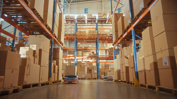 istock Future Technology: Automated Modern Retail Warehouse Delivery AGV Robots Transporting Cardboard Boxes in Distribution Logistics Center. Automated Guided Vehicles Delivering Goods, Products, Packages 1349338720
