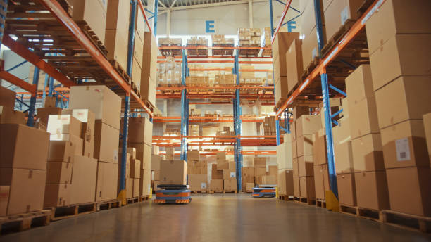 future technology: automated modern retail warehouse delivery agv robots transporting cardboard boxes in distribution logistics center. automated guided vehicles delivering goods, products, packages - logistical imagens e fotografias de stock