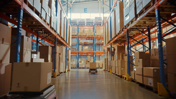 istock Future Technology 3D Concept: Automated Modern Retail Warehouse AGV Robots Transporting Cardboard Boxes in Distribution Logistics Center. Automated Guided Vehicles Delivering Goods, Products, Packages 1349338726