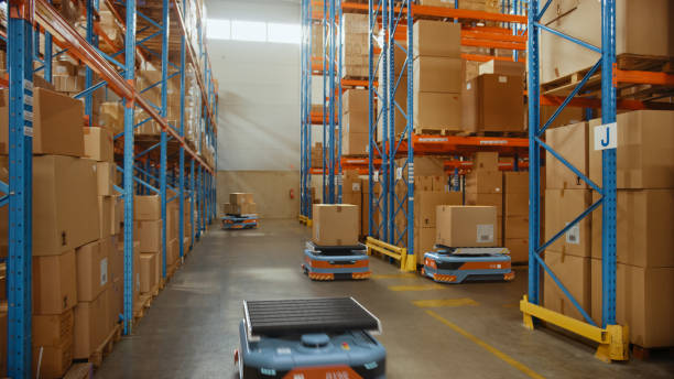 istock Future Technology 3D Concept: Automated Modern Retail Warehouse AGV Robots Transporting Cardboard Boxes in Distribution Logistics Center. Automated Guided Vehicles Delivering Goods, Products, Packages 1349338732