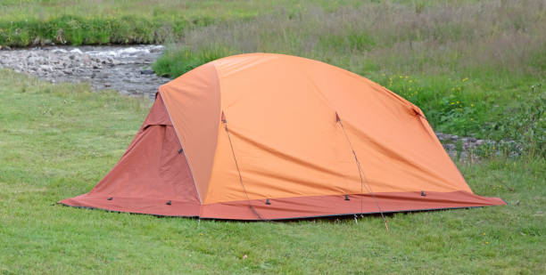 Orange dome tent on green grass in camping site, Iceland