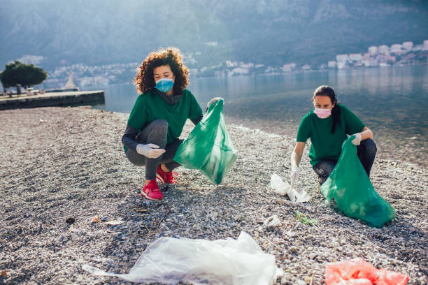 istock Young female volunteers collecting plastic garbage at beach 1349341658