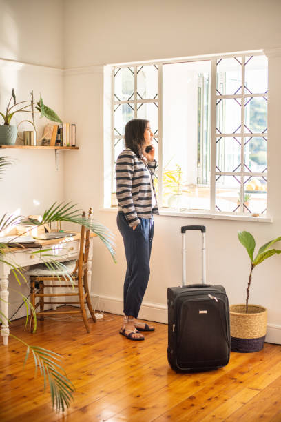 istock Young woman with a suitcase talking on her phone in her vacation accommodation 1349341679