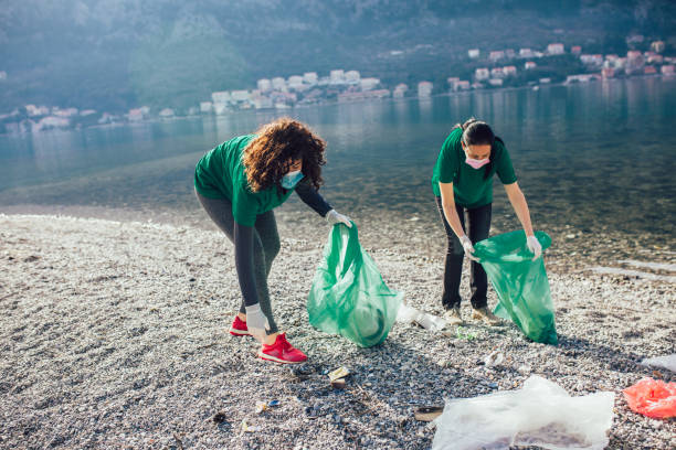 istock Young female volunteers collecting plastic garbage at beach 1349341795