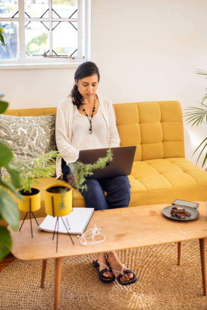 istock Young woman using a laptop while working remotely from home 1349341922