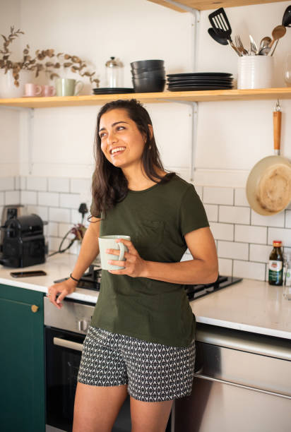 istock Young woman in pajamas smiling while drinking coffee in her kitchen 1349342967