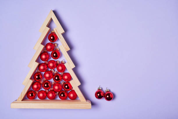 istock Wooden christmas tree with red christmas balls inside on pink background with copy space 1349343081