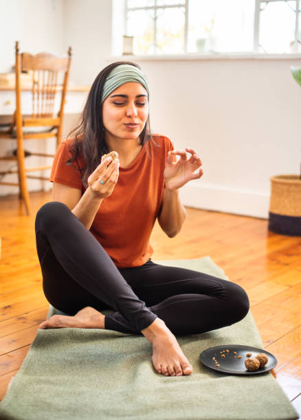 Smiling young woman eating a healthy snack after a home yoga session stock photo