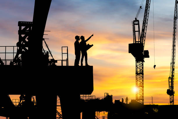 istock Silhouette of Engineer and worker checking project at heavy infrastructure building site background, construction site at sunset in evening time. 1349343786
