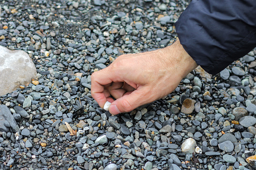 Man hand picking up stones from river beach