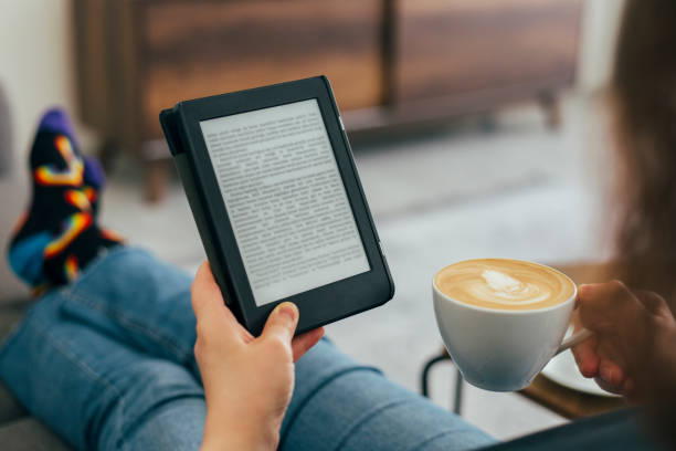 Woman Reading E-Book at Home Woman sitting on sofa and reading e-book at home. kindle and ook stock pictures, royalty-free photos & images