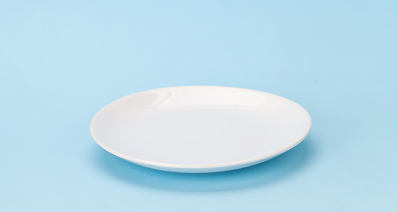 Empty white plate on blue background with space for your meal