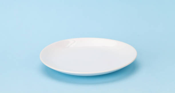 Empty white plate on blue background Empty white plate on blue background with space for your meal empty plate stock pictures, royalty-free photos & images