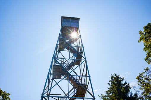 The sun shines through the Red Hill Fire Tower in the Catskills Mountains, in Claryville, New York during a summer afternoon. The fire tower is a popular attraction for hikers.