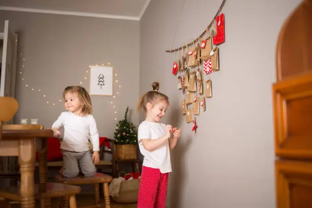 children in kitchen in dining room playing against background of Christmas decor.