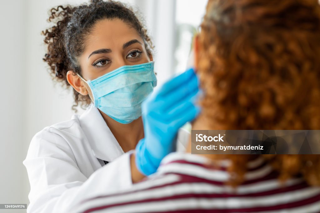 Doctor wearing surgical mask examining Doctor Stock Photo