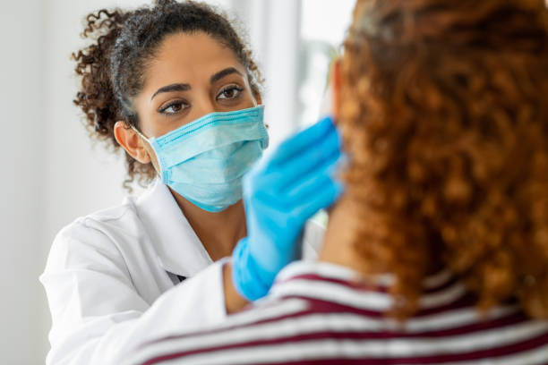Doctor wearing surgical mask examining Doctor wearing surgical mask examining dental hygienist stock pictures, royalty-free photos & images