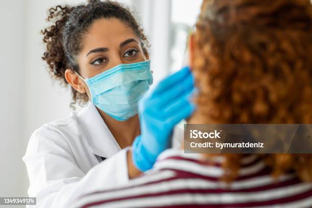 Doctor Wearing Surgical Mask Examining Stock Photo - Download Image Now - Doctor, Patient, Protective Face Mask